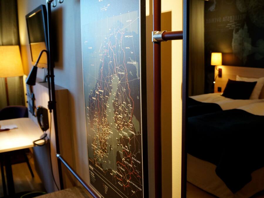 Habitación de hotel con cama, escritorio y un mapa de Finlandia en la pared.