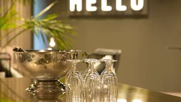 A reception area with a 'HELLO' sign, a silver bowl, and three wine glasses on a reflective surface.