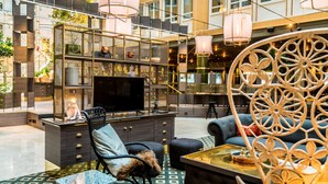 A modern lounge area with a sofa, chairs, a coffee table, and a TV. - Scandic Skellefteå (Skelleftea)