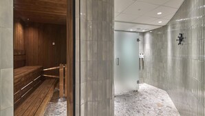 A modern interior with a wooden bench, a tiled wall, and a shower area. - Scandic Skellefteå (Skelleftea)