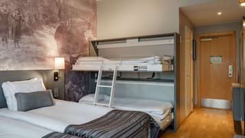 A hotel room with bunk beds, a wooden door, and a wall mural.