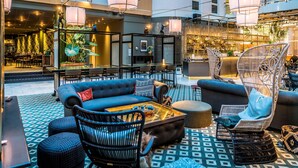 A modern lounge area with seating arrangements, a bar, and a patterned floor. - Scandic Skellefteå (Skelleftea)