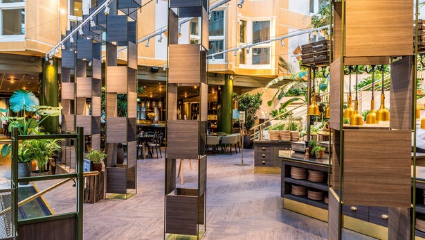 A modern hotel lobby with a central staircase, wooden paneling, and potted plants. - Scandic Skellefteå (Skelleftea)