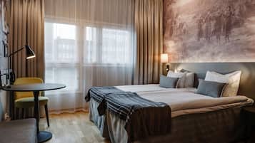 Une chambre d’hôtel avec un grand lit, une petite table avec une chaise, une lampe et un tableau au mur.
