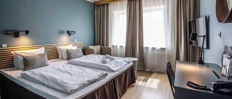 Habitación de hotel con dos camas, un escritorio, una silla, un teléfono y una televisión.