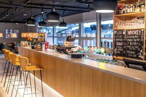 Zona de bar con mostrador, taburetes y una variedad de botellas de licor.