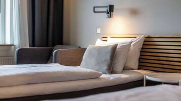 Una habitación de hotel moderna con una cama bien hecha, un sofá y una mesita.
