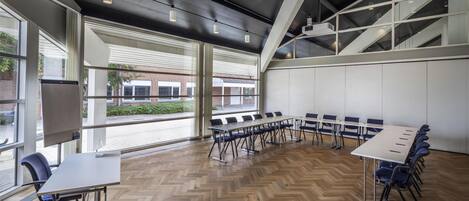 A conference room with a long table, chairs, and a projector screen.