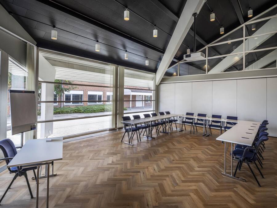 A conference room with a long table, chairs, and a projector screen.