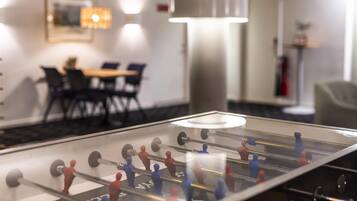 Una mesa de futbolín en una habitación de hotel, con una zona de comedor al fondo.
