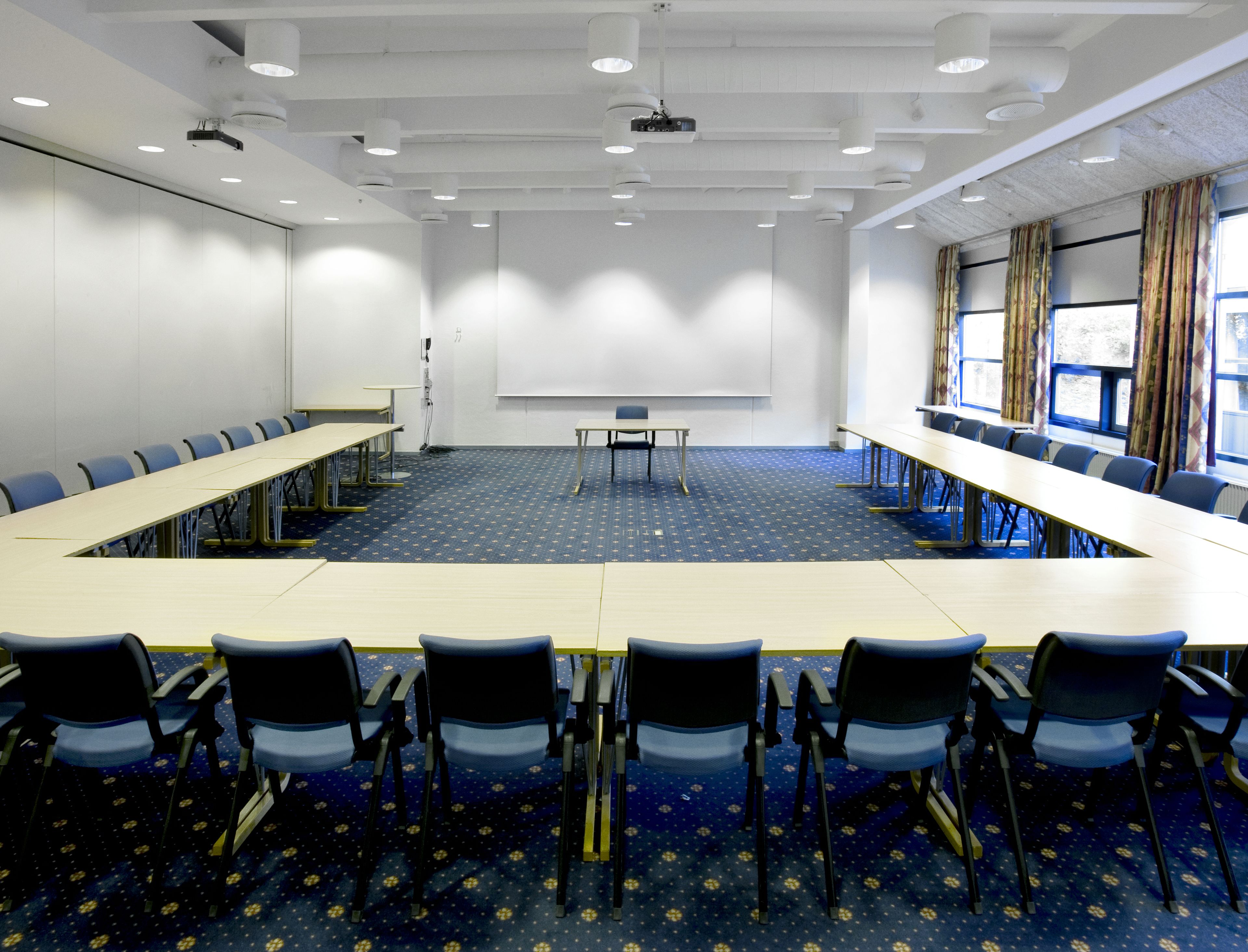 A conference room with a long table, chairs, a projector, and a whiteboard.