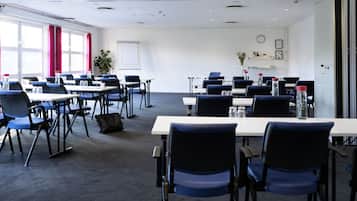 A conference room with tables and chairs, a whiteboard, and a clock on the wall.