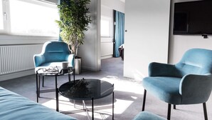 A modern living room with two blue armchairs, a coffee table, and a potted plant. - Scandic Odense (Odense)