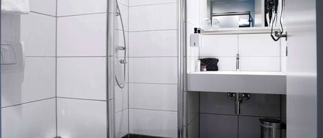 A modern bathroom with a glass-enclosed shower, a white toilet, and a sink with a mirror above it.