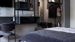A modern hotel room with a bed, a desk with a chair, a TV, and a wardrobe. - Scandic Odense (Odense)