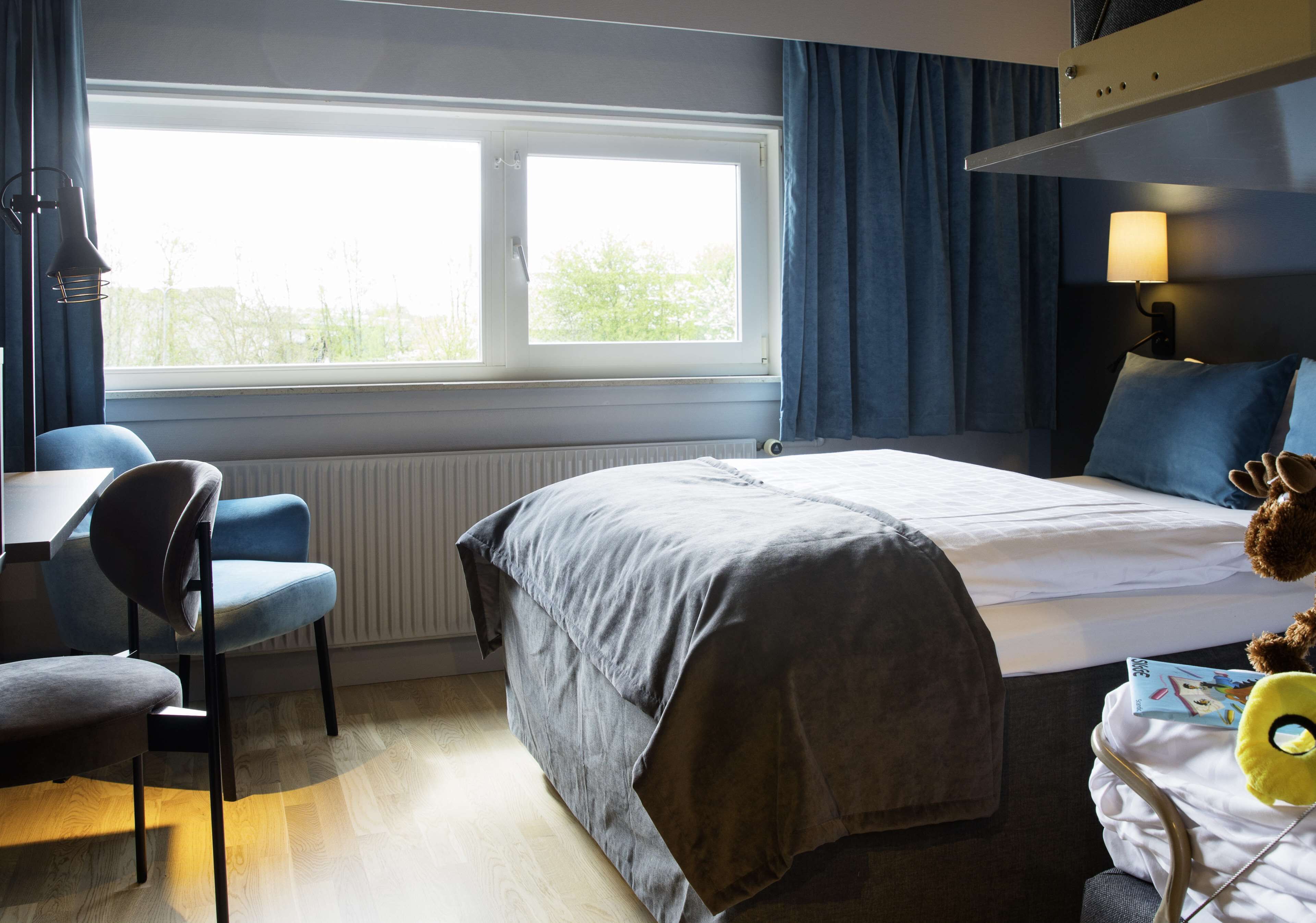 A hotel room with a bed, a desk, and a chair.