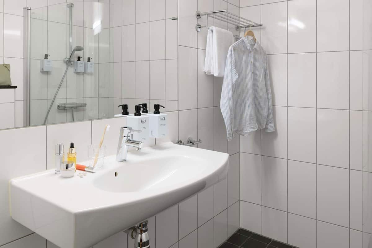 A modern bathroom with a white sink, a glass shower enclosure, and a towel rack.