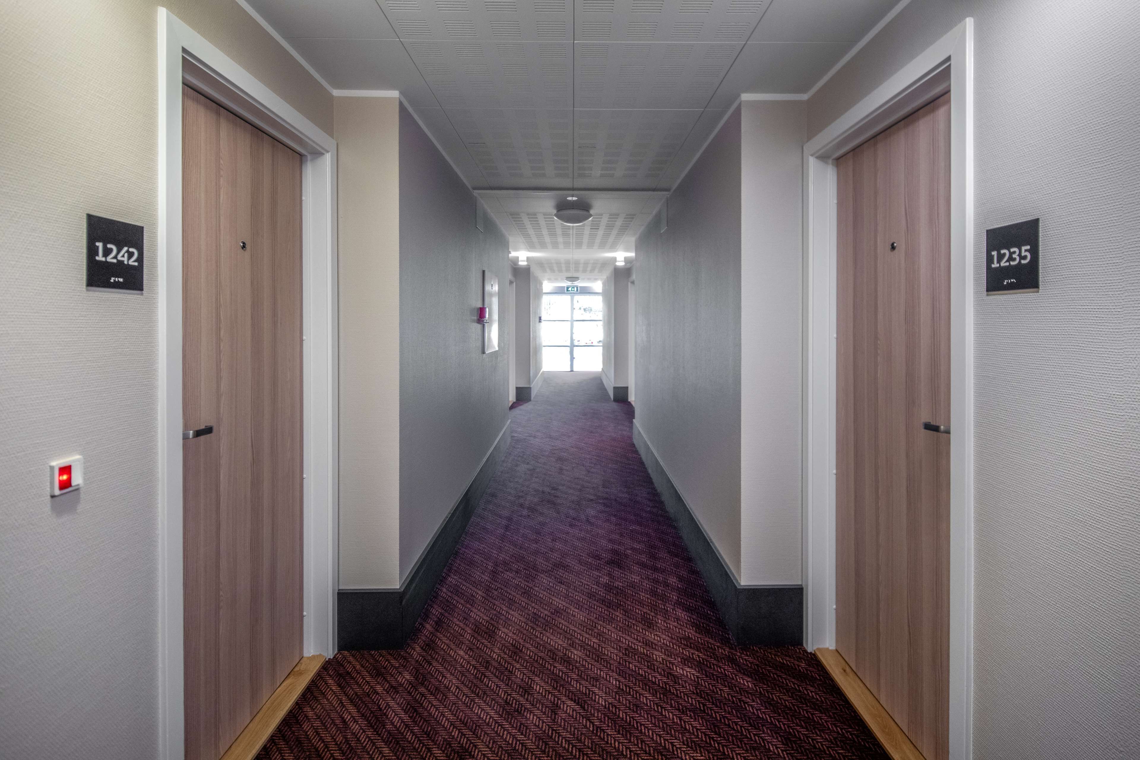 A hallway with carpeted floors, wooden doors, and numbered signs indicating room numbers 1242 and 1235.
