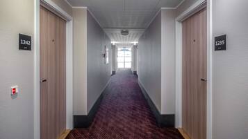 A hallway with carpeted floors, wooden doors, and numbered signs indicating room numbers 1242 and 1235.