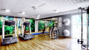 Una sala de gimnàstica amb cintes de córrer, una banca i màquines de musculació.