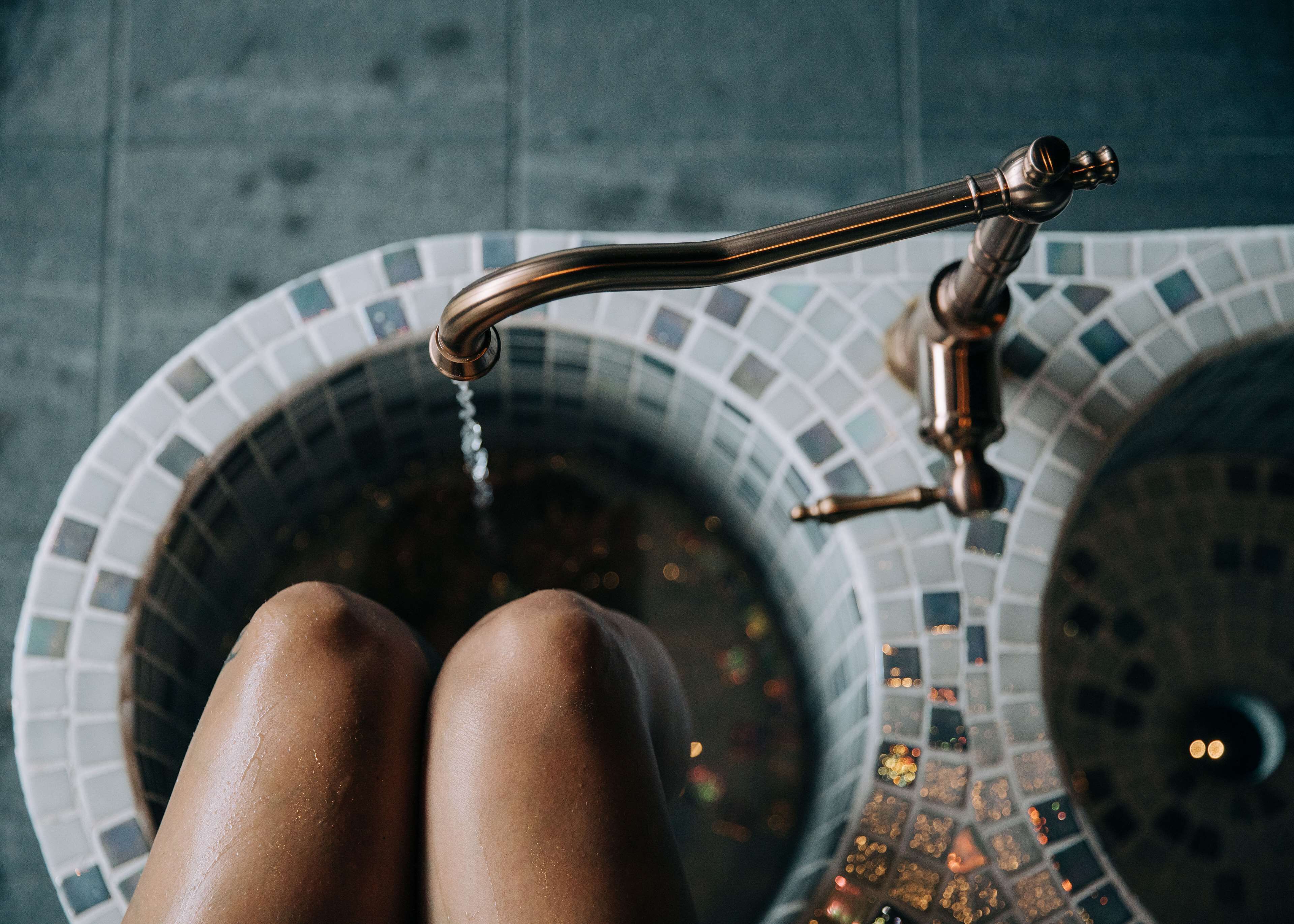 A bathroom with a mosaic tile sink and a brass faucet.