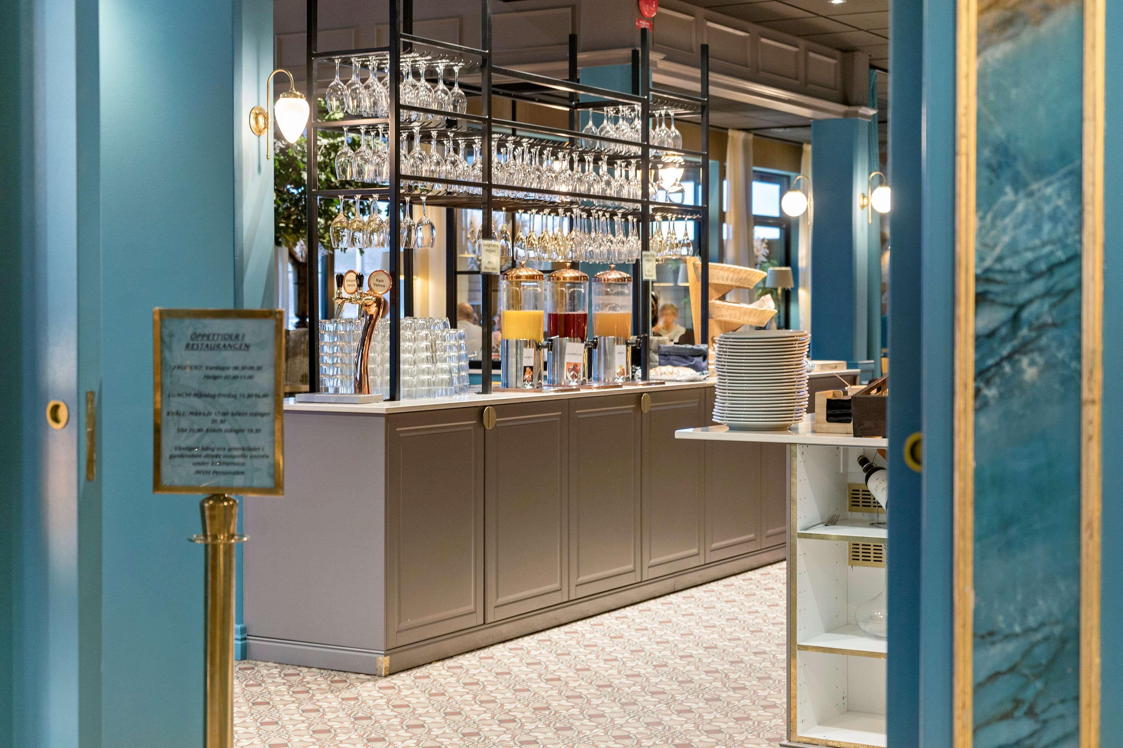 A bar area with shelves of glasses and bottles, a counter with stacked glasses, and a menu sign.