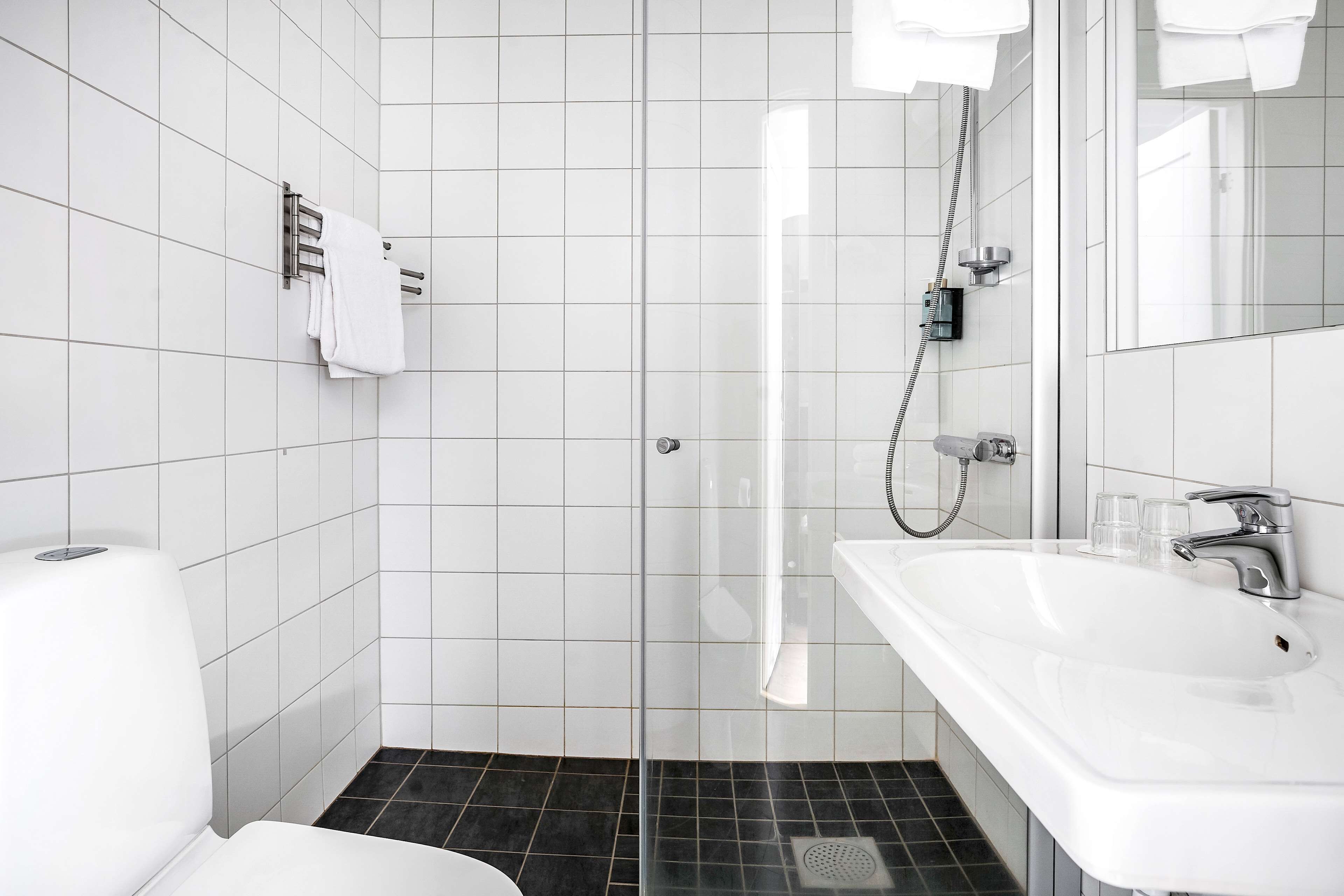 Une salle de bain moderne avec une douche à parois de verre, un lavabo blanc avec un miroir et des toilettes.