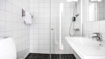Une salle de bain moderne avec une douche à parois de verre, un lavabo blanc avec un miroir et des toilettes.
