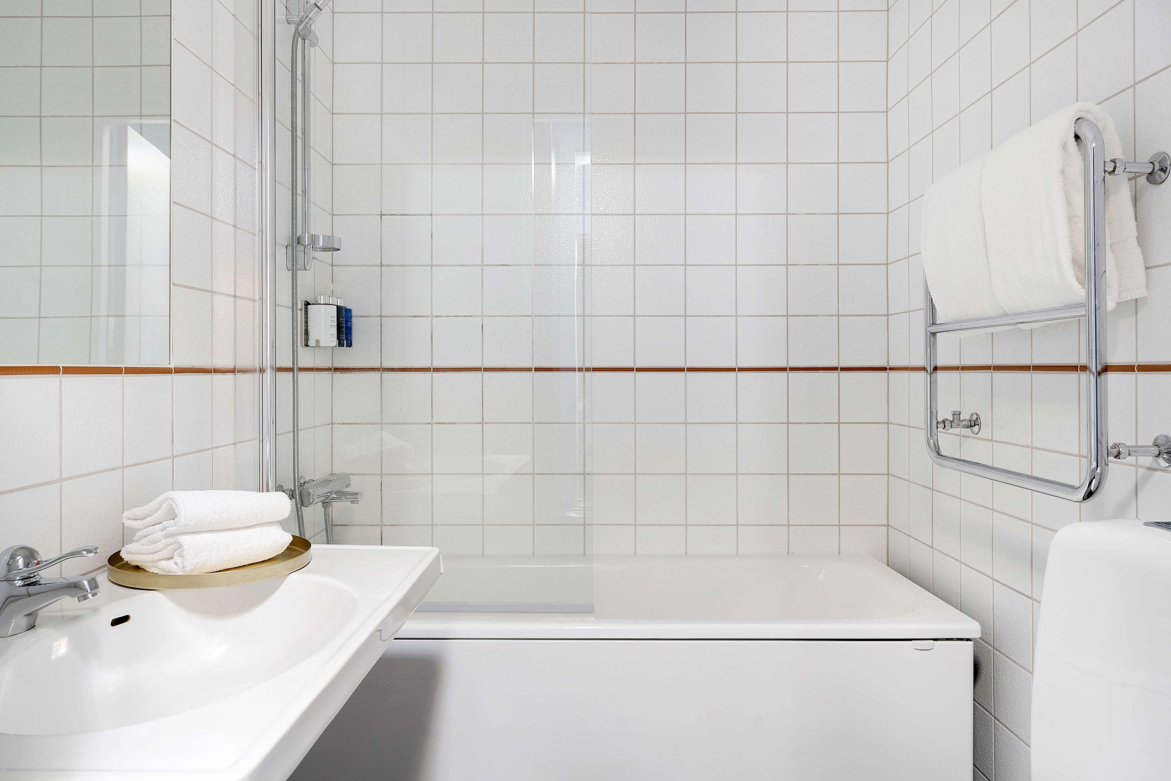 A modern bathroom with a white sink, a bathtub, and a shower.