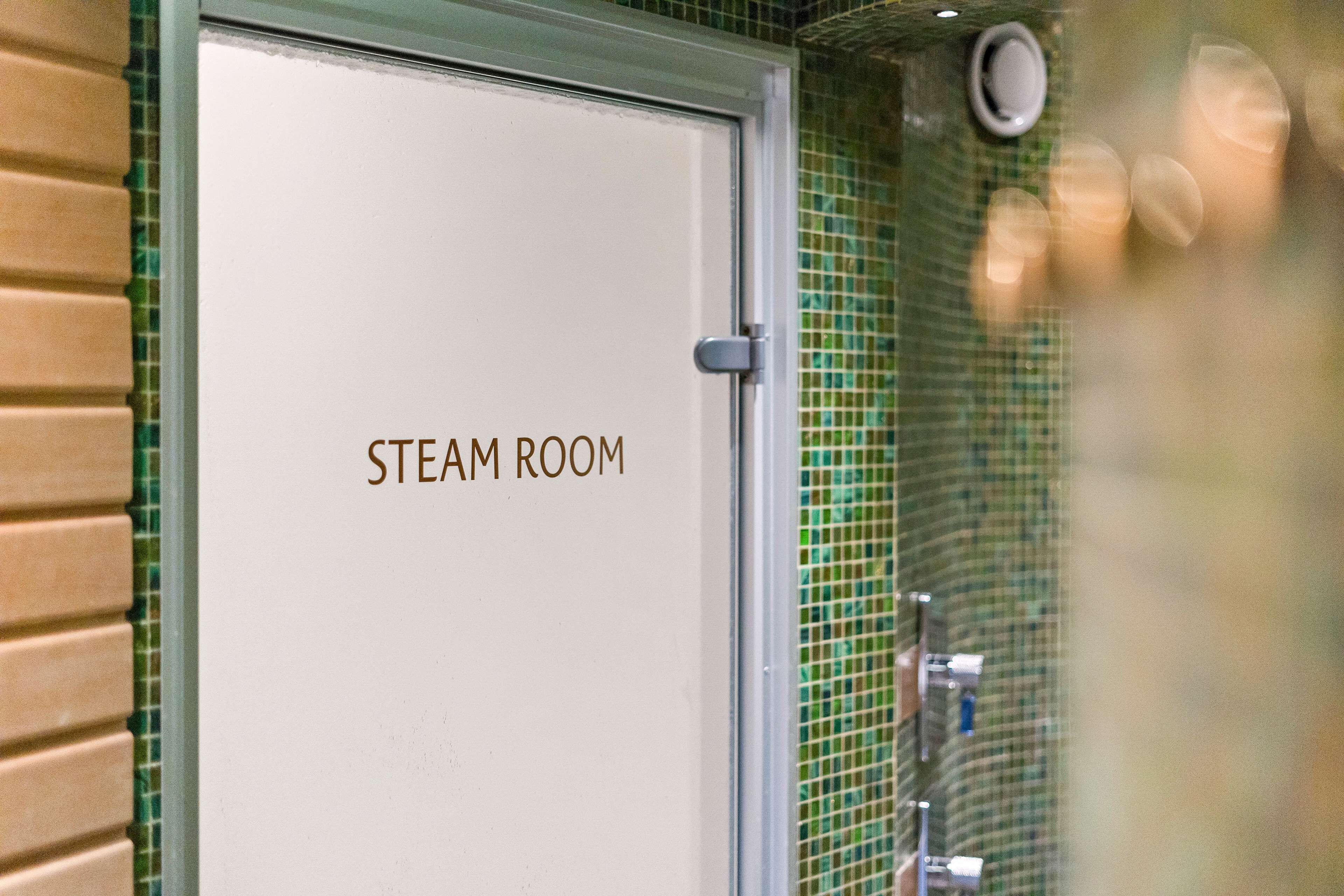 A door labeled "STEAM ROOM" with a tiled wall and a window.
