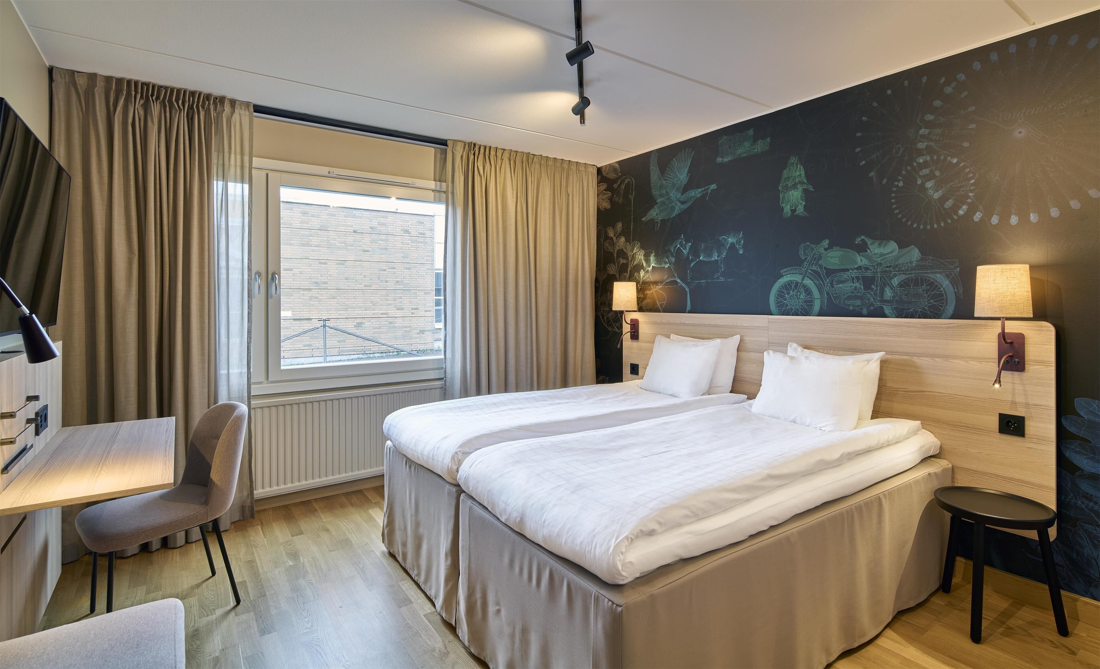 A hotel room with a large bed, a desk, and a chair.