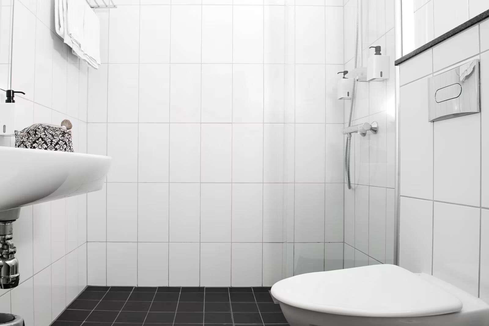 A modern bathroom with a white sink, toilet, and shower.