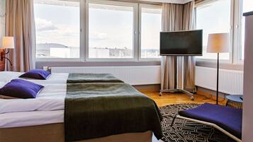 Habitación de hotel con una cama grande, dos almohadas, televisión y vistas a la ciudad.