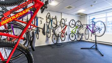 A room with bicycles mounted on the wall and a red bicycle in the foreground.