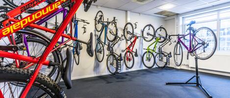 Une pièce dans laquelle des vélos sont accrochés au mur, et un vélo rouge se trouve au premier plan.