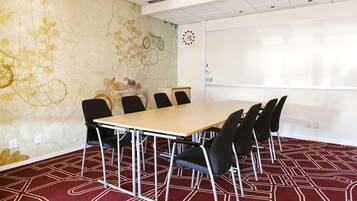 A conference room with a long table, black chairs, a whiteboard, and a clock on the wall.