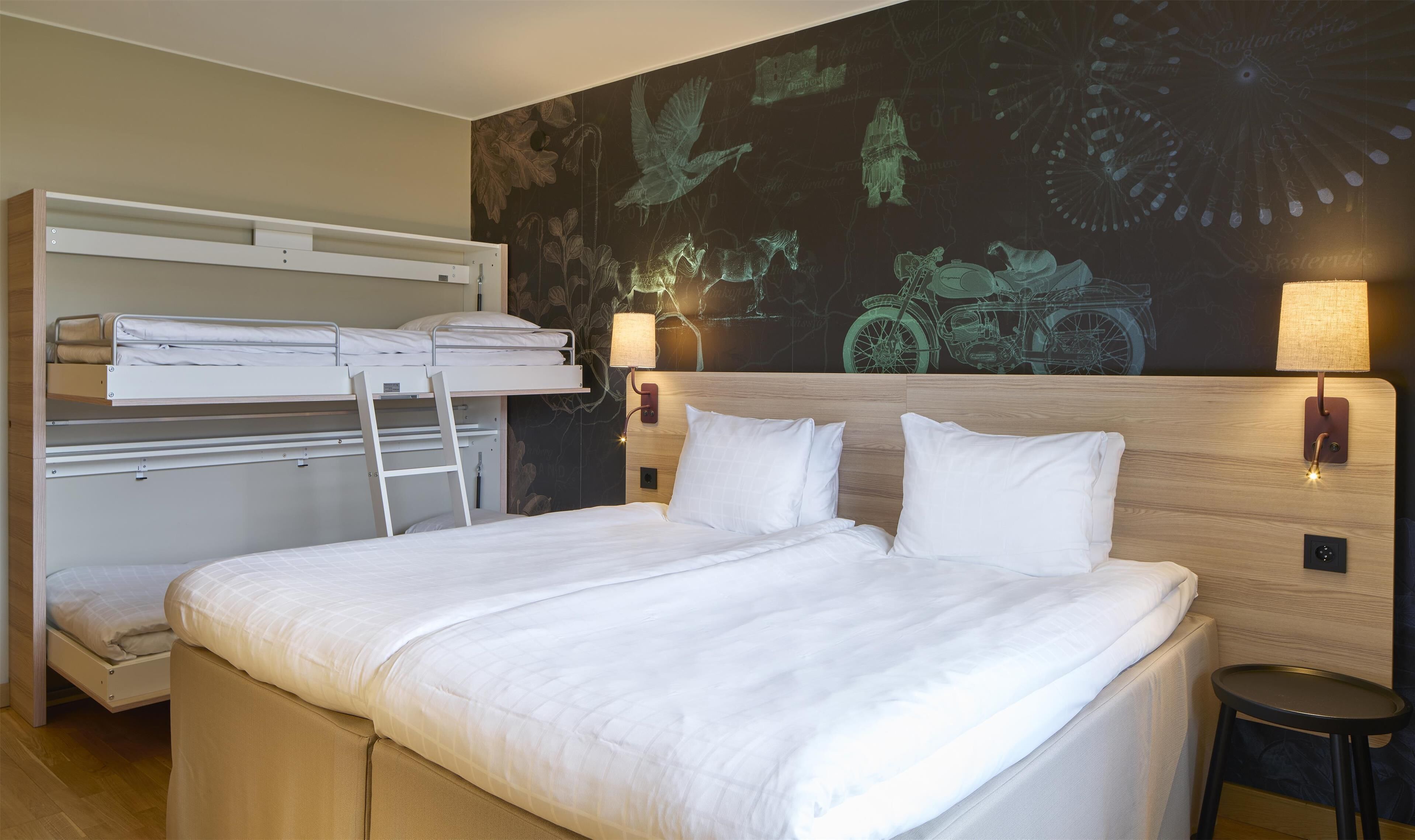 Una habitación de hotel con literas, una cama grande y un mural en la pared.