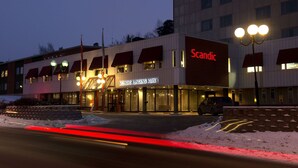 Een hotel met een bord waarop staat 'Scandic Kongsberg Kurva' in de schemering.