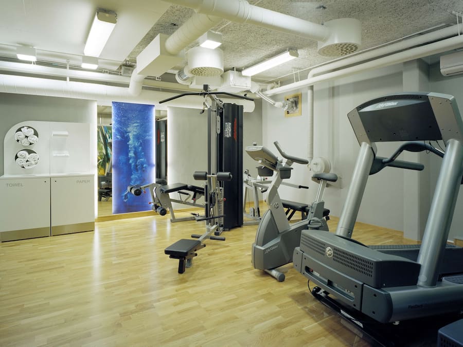 Ein Fitnessraum mit Trainingsgeräten, Handtuch- und Papierabroller sowie ein großes Fenster mit Blick ins Freie.