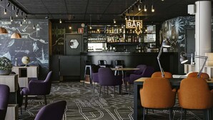 Een barruimte met een kaart aan de muur, barstoelen en een toog met flessen.