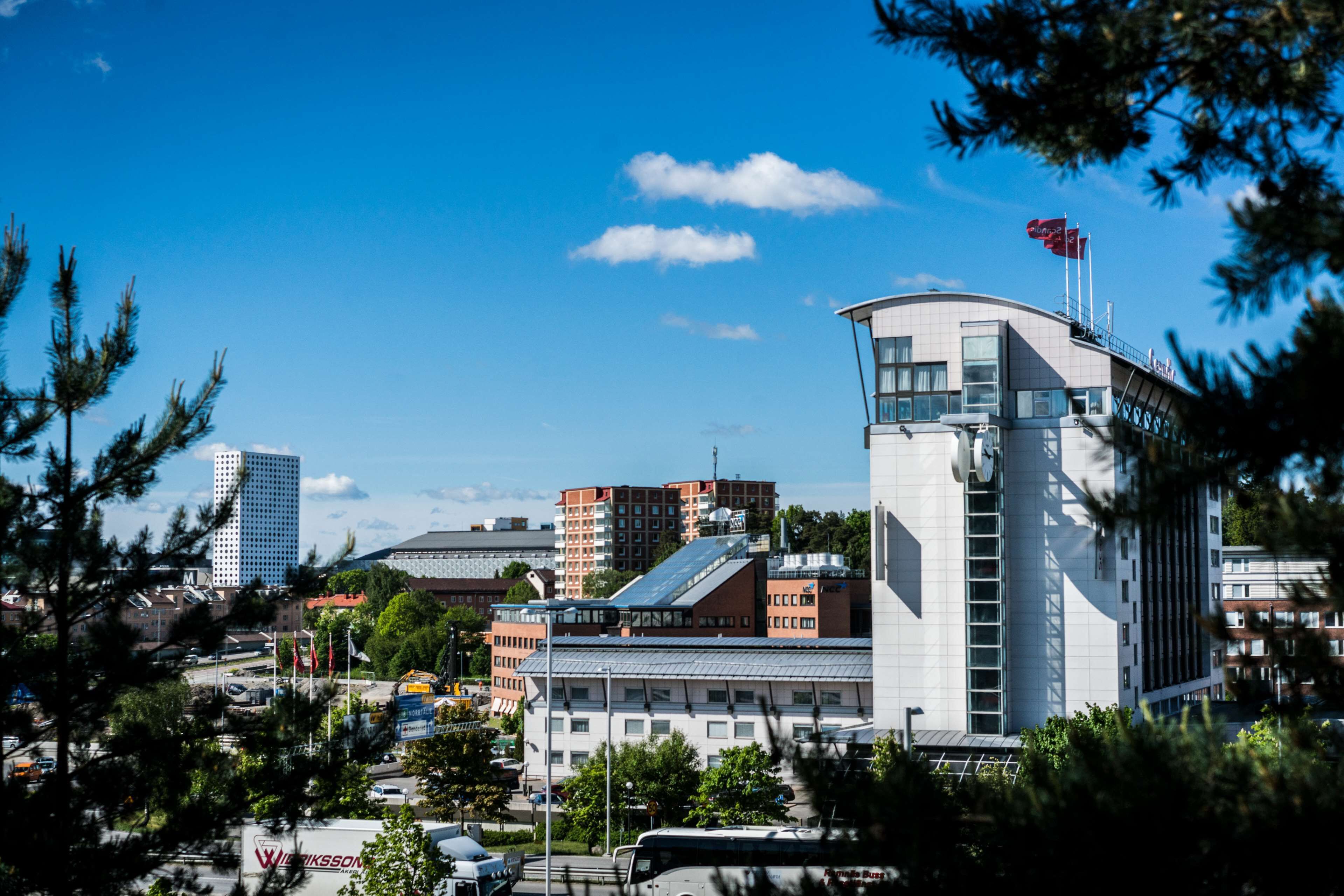 A modern building with a prominent tower, surrounded by other buildings and trees.