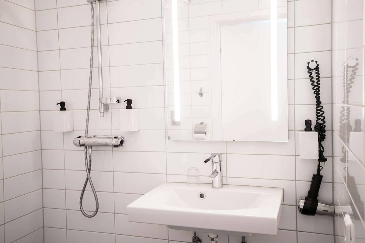 Un bagno moderno con un lavandino bianco, uno specchio e una doccia.