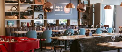 A restaurant with tables and booths, a foosball table, and shelves with various items.