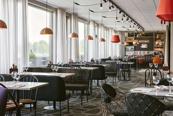 A restaurant with long tables, booths, and hanging pendant lights. - Scandic Klarälven (Karlstad)