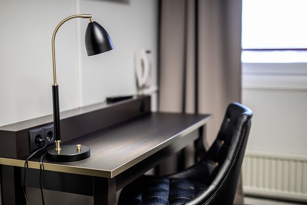 A modern desk with a lamp, a chair, and a power outlet.