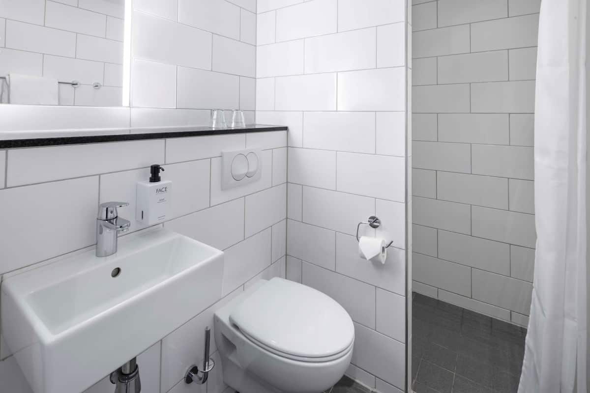 A modern bathroom with a white sink, toilet, and shower area.