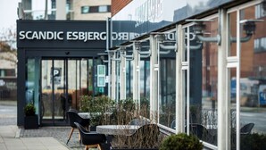 An outdoor seating area with tables and chairs, a glass storefront, and a sign reading "SCANDIC ESBJERG." - Scandic Olympic (Esbjerg)