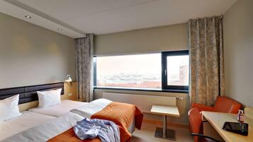 Ett hotellrum med två sängar, ett litet bord, en stol och ett fönster med utsikt.