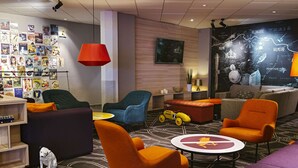 A modern lounge area with a variety of seating options, a wall decorated with travel posters, and a large map mural. - Scandic Backadal (Hisings Backa)