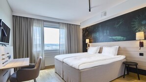 A hotel room with a bed, a desk, a chair, a TV, and a window with curtains. - Scandic Backadal (Hisings Backa)